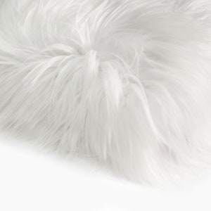 May include: White faux fur fabric with a soft, fluffy texture. The fur is long and dense, creating a luxurious look and feel.