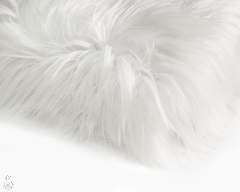 May include: White faux fur fabric with a soft, fluffy texture. The fur is long and dense, creating a luxurious look and feel.