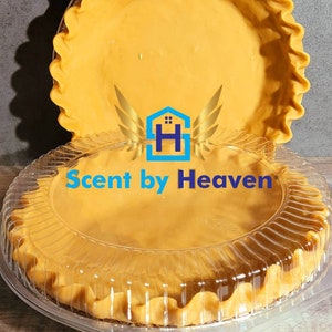 May include: Two empty pie crusts in clear plastic containers. The crusts are golden brown and have a fluted edge. The containers have a clear plastic lid. The logo "Scent by Heaven" is printed on the bottom crust.