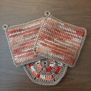 May include: Two crocheted pot holders with a brown and red striped pattern and a crocheted round pot holder with a brown and red spiral pattern.
