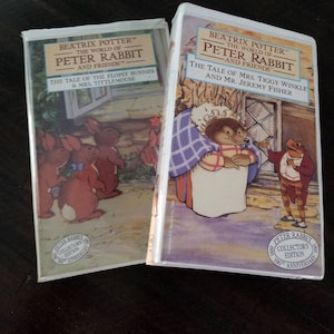 May include: Two VHS tapes from "The World of Peter Rabbit" series. One tape features "The Tale of the Flopsy Bunnies & Mrs. Tittlemouse," and the other, "The Tale of Mrs. Tiggy Winkle and Mr. Jeremy Fisher." Both are collector's editions.