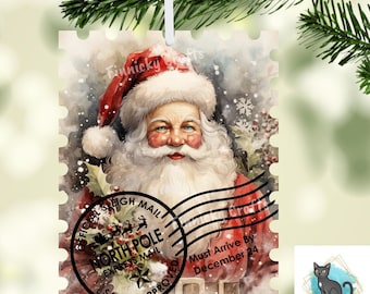 May include: A rectangular Christmas ornament shaped like a postage stamp featuring a watercolour illustration of Santa Claus. A black North Pole postmark stamp with the text Official Sleigh Mail and Must Arrive By December 24 is visible.