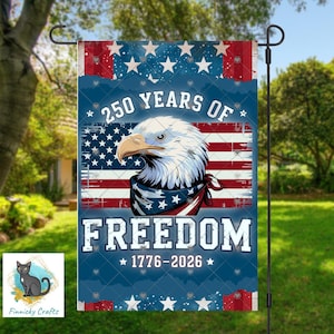 Puede incluir: Una bandera de jardín con un diseño patriótico. Presenta un águila calva con un pañuelo delante de una bandera estadounidense. El texto dice "250 YEARS OF FREEDOM 1776-2026" en blanco. El fondo es azul con estrellas blancas y rayas rojas.