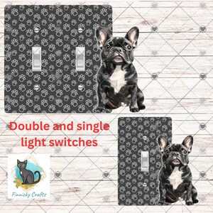 Op de afbeelding: Decoratieve lichtschakelaars met een zwart-wit Franse bulldog en pootafdrukpatroon. De afbeelding toont een dubbele schakelaar en een enkele schakelaar. De tekst "Double and single light switches" is zichtbaar.
