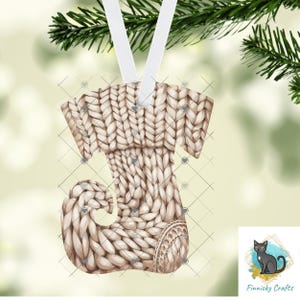 May include: A Christmas stocking ornament with a knitted design in shades of beige and white. The ornament is hanging from a white ribbon and is decorated with small heart shapes. The ornament is a festive decoration.