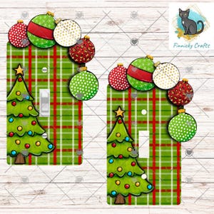 May include: Christmas-themed light switch covers. The covers feature a green and red plaid pattern, a Christmas tree, and decorative ornaments in red, green, and gold. The brand name "Finnicky Crafts" is visible in the corner.