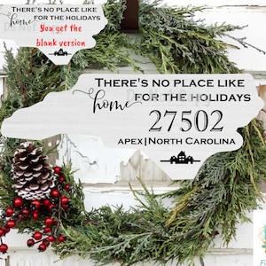 Puede incluir: Un recorte de madera blanco del estado de Carolina del Norte con el texto "THERE'S NO PLACE LIKE HOME FOR THE HOLIDAYS" y el código postal "27502" y la ciudad y el estado "APEX | NORTH CAROLINA". El recorte está decorado con un pequeño icono de casa y está rodeado de una corona verde.