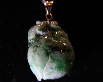 May include: A green jade pendant carved in the shape of a flower. The pendant is attached to a gold chain.