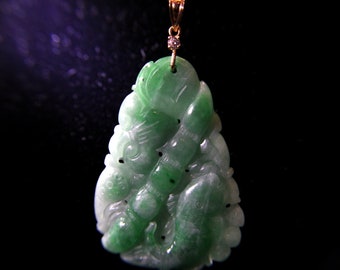 May include: A jade pendant with a carved design, featuring shades of green and white. The pendant is suspended from a gold chain with a small diamond accent. The intricate carving depicts a floral or organic motif.