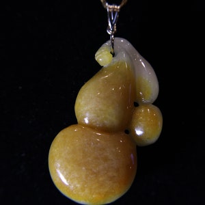 May include: A yellow jade pendant carved in the shape of a gourd, a symbol of good fortune and prosperity in Chinese culture.
