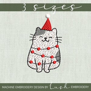 Op de afbeelding: Een witte kat met een rode kerstmanmuts en een string rode lampjes om zijn lichaam. De kat zit met gekruiste poten en heeft een gelukkige uitdrukking op zijn gezicht. 3 maten.