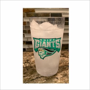 May include: A clear plastic cup with ice and a green and white logo that says "Edina Giants".