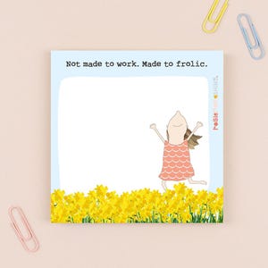 May include: A square notepad with a light blue background and the text "Not made to work. Made to frolic." A cartoon illustration of a person in a pink dress is jumping in front of a field of yellow flowers.