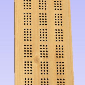 May include: A wooden board with a pattern of evenly spaced holes, resembling a game board. The holes are arranged in a unique design, with a central oval shape and two parallel lines on either side.