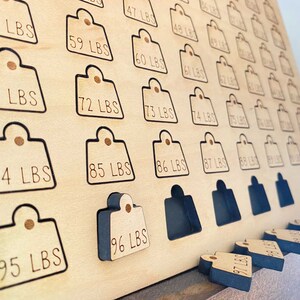 May include: A wooden board with a grid of numbered weight tags. The tags are labeled in pounds from 58 to 96. The board is made of light wood and has a black border around each tag. The tags are missing from the board and are shown below the board. The tags are black and have white text.