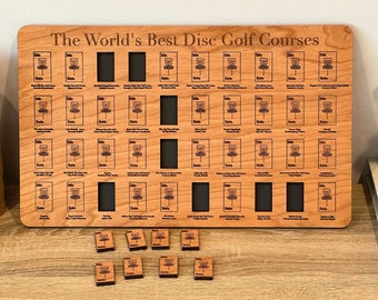 Può includere: Una targa in legno con la scritta "The World's Best Disc Golf Courses" incisa in alto. La targa presenta piccoli quadrati con grafiche di canestri da disc golf e nomi di campi. Diversi piccoli segnapunti per campi da disc golf in legno sono in basso.