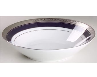Op de afbeelding: Witte keramische kom met een marineblauwe band en zilveren rand. De kom heeft een eenvoudig, elegant ontwerp, geschikt voor het serveren van soepen of salades. De zilveren rand heeft een delicaat, herhalend patroon.
