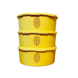 May include: Three yellow plastic storage containers with a brown floral design stacked on top of each other.