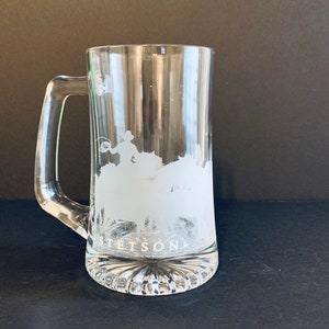 Peut inclure: Mug &agrave; bi&egrave;re en verre transparent avec une anse. Le mug pr&eacute;sente un motif givr&eacute; d'un cow-boy attrapant un taureau, avec le mot "STETSON" en dessous. La base du mug a un motif d&eacute;coratif &agrave; nervures.