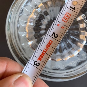 Peut inclure: Un objet en verre transparent avec un motif textur&eacute; est mesur&eacute; avec un m&egrave;tre ruban Craftsman. Le ruban &agrave; mesurer indique une mesure d'environ 7,6 cm. L'objet est sur une surface sombre.