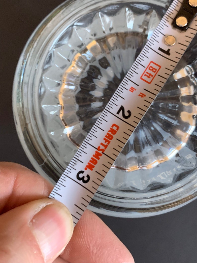 Peut inclure: Un objet en verre transparent avec un motif textur&eacute; est mesur&eacute; avec un m&egrave;tre ruban Craftsman. Le ruban &agrave; mesurer indique une mesure d'environ 7,6 cm. L'objet est sur une surface sombre.