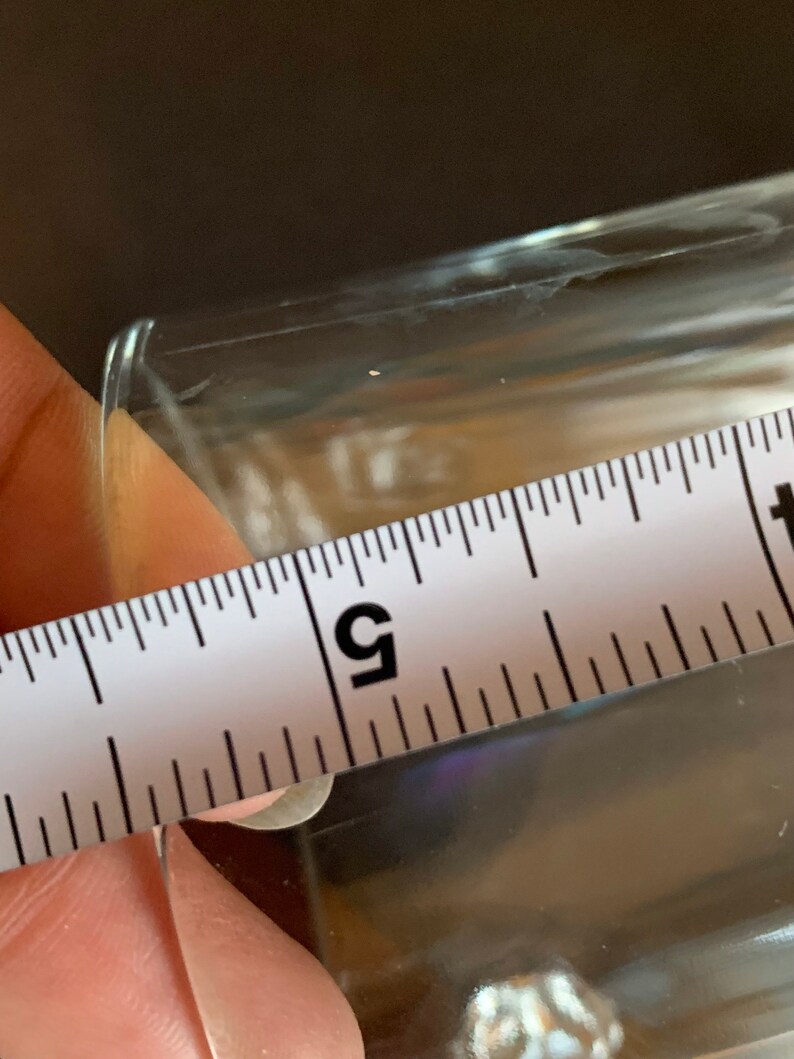 Peut inclure: Un objet clair et rectangulaire est mesur&eacute; avec une r&egrave;gle blanche. La r&egrave;gle indique une mesure d'environ 12,7 cm. L'objet est transparent et semble &ecirc;tre en verre ou dans un mat&eacute;riau similaire.