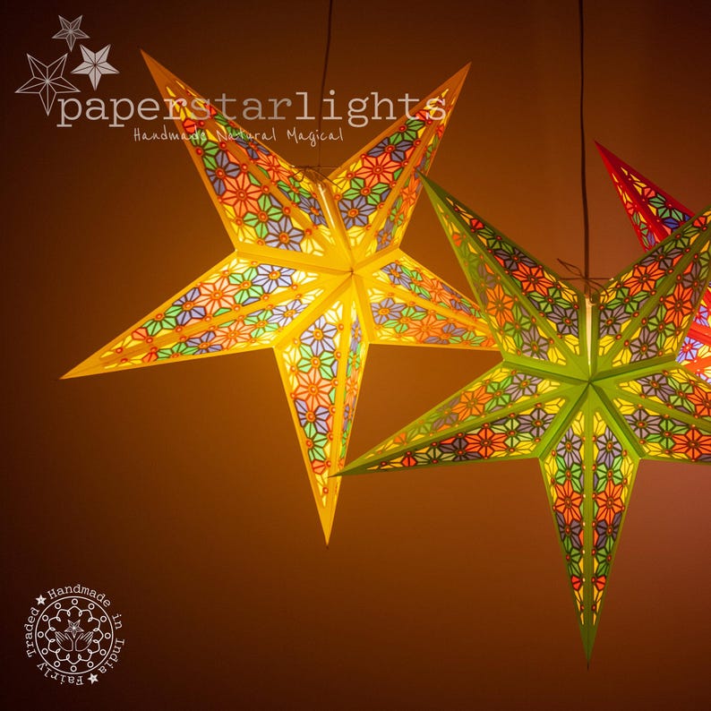 K&ouml;nnte beinhalten: Drei Papierlaternen in Sternform h&auml;ngen von der Decke. Die Sterne sind aus d&uuml;nnem Papier gefertigt und haben ein farbenfrohes geometrisches Muster. Die Sterne werden von innen beleuchtet und erzeugen so ein warmes Leuchten. Der Text "paperstarlights Handmade Natural Magical" ist in der oberen linken Ecke des Bildes sichtbar.