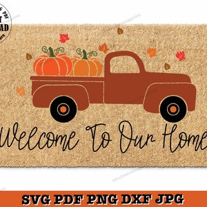 Könnte beinhalten: Ein brauner Pickup-Truck mit einer Ladefläche voller orangefarbener Kürbisse und roten und orangefarbenen Herbstblättern. Der Truck steht auf einer braunen Fußmatte mit dem Text "Welcome To Our Home" in Schwarz.