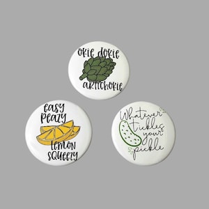 May include: Three round white buttons with black text and green and yellow illustrations. The first button says "okie dokie artichoke" and has a green artichoke illustration. The second button says "easy peasy lemon squeezy" and has a yellow lemon illustration. The third button says "Whatever tickles your pickle" and has a green pickle illustration.