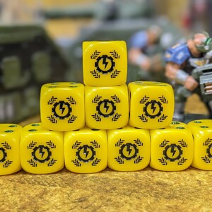 May include: A set of ten yellow dice with black lightning bolt symbols. The dice are stacked in a pyramid shape.