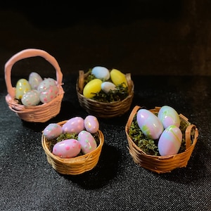 May include: Four miniature wicker baskets filled with pastel colored Easter eggs. The baskets are filled with green moss and the eggs are decorated with polka dots and swirls.