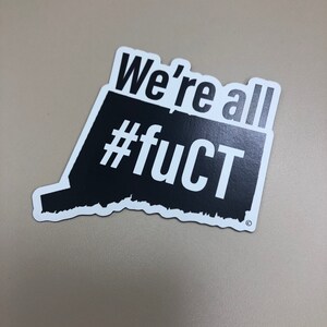May include: Black and white sticker with the text "We're all #fuCT" in a distressed font.