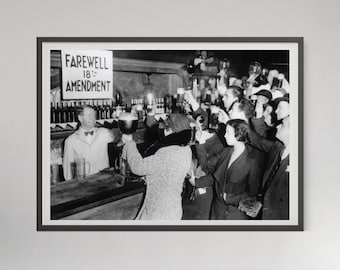 May include: A black and white photograph in a dark frame showing a crowded bar scene with people raising beer mugs. A sign on the wall reads FAREWELL 18TH AMENDMENT. A bartender in a light-colored jacket stands behind the counter with many bottles.