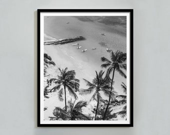 Könnte beinhalten: Schwarzweißes Luftbild eines Strandes mit Palmen und Menschen beim Surfen. Das Foto ist in einem schwarzen Rahmen gerahmt.