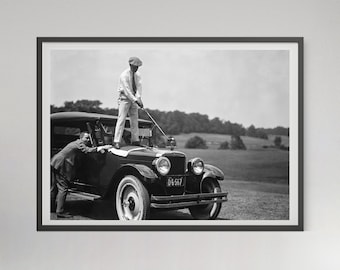 Pode incluir: Uma fotografia a preto e branco de dois homens a pé ao lado de um carro antigo. Um homem está segurando um taco de golfe e está em pé sobre o capô do carro. O outro homem está em pé no chão ao lado do carro. O carro tem uma placa de matrícula que diz "DG 567".