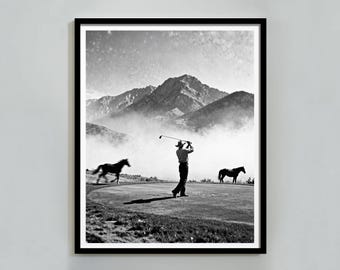 May include: Black and white framed print of a golfer swinging a club on a green, with two horses and a mountain range in the background. The image has a vintage aesthetic.