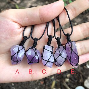 Puede incluir: Cinco collares de cristal de amatista con cordón negro y nudos de macramé. Los cristales son de diferentes formas y tamaños. Los collares están etiquetados de la A a la E.