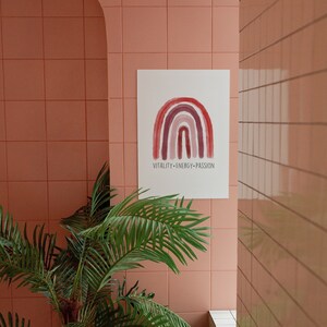May include: A watercolor print featuring a rainbow design in shades of red and purple, with the words "VITALITY-ENERGY-PASSION" below. The print hangs on a pink tiled wall, with a potted palm tree in the foreground.