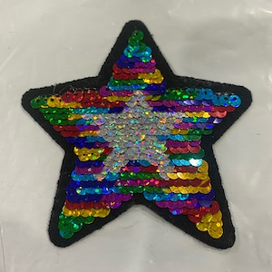 May include: A rainbow sequin star patch with a white sequin star in the centre. The patch is made of black felt and is ideal for adding a touch of sparkle to any project.
