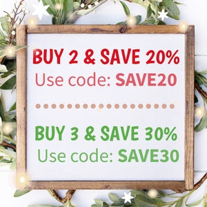 May include: A white sign with a wooden frame, surrounded by greenery and lights. The sign reads "BUY 2 & SAVE 20% Use code: SAVE20" and "BUY 3 & SAVE 30% Use code: SAVE30".