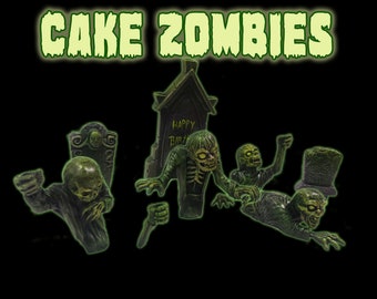 May include: Green zombie cake toppers with a tombstone that says "Happy Birthday".