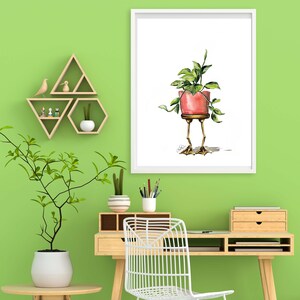 May include: A watercolor illustration of a potted plant with legs. The plant is in a red pot and has green leaves. The plant is standing on two legs with feet. The illustration is framed in a white frame and is hanging on a green wall.