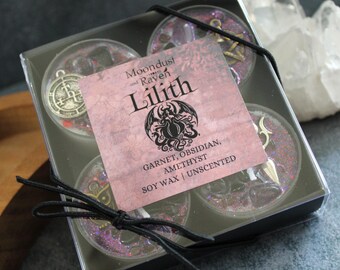 Könnte beinhalten: Ein Set mit vier Sojawachs-Duftkerzen in einer durchsichtigen Plastikbox. Die Kerzen sind rosa und lila mit Glitzer und haben eingebettete Charms. Die Box hat ein Etikett mit der Aufschrift "Moondust and Raven Lilith Garnet, Obsidian, Amethyst Soy Wax | Unscented".