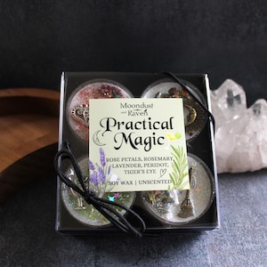 Könnte beinhalten: Ein Set mit vier Teelichtern aus Sojawachs in einer durchsichtigen Plastikbox. Jede Kerze hat ein anderes Design mit natürlichen Elementen wie Rosenblüten, Rosmarin, Lavendel, Peridot und Tigerauge. Die Box trägt ein Etikett mit der Aufschrift "Moondust and Raven Practical Magic" und listet die Zutaten und "Sojawachs | Ungeparfümt" auf.