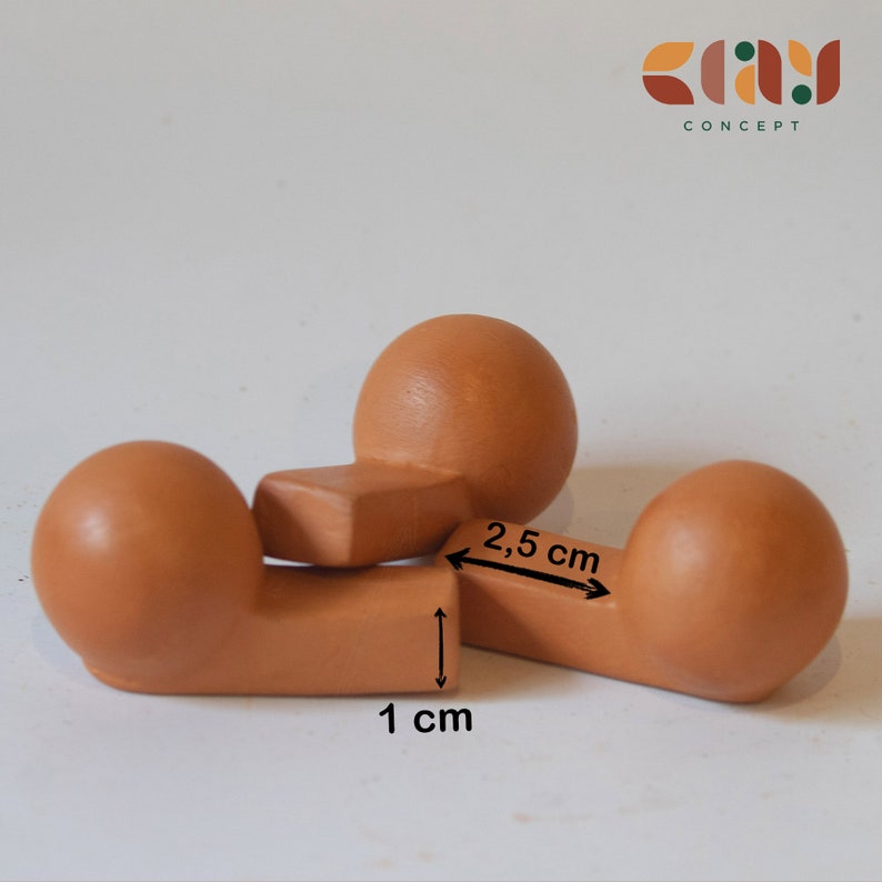 May include: Three terracotta-colored ceramic spheres, each with a flat, rectangular base. The spheres are arranged in a triangular shape, with the bases of two spheres forming a line. The bases are 1 inch apart, and the spheres are 2.5 inches apart.