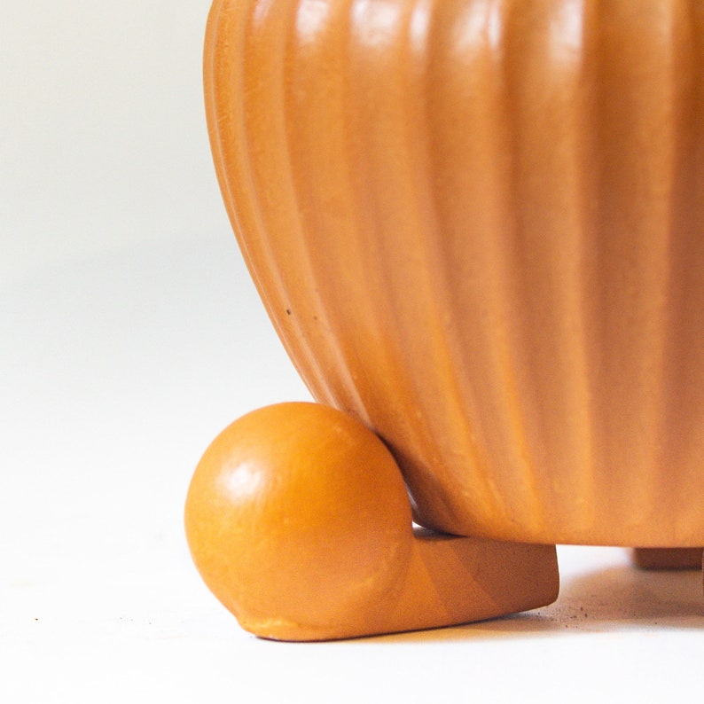 May include: A terracotta-colored ceramic planter with a ribbed design and a rounded base. The planter has a smooth, glossy finish and is perfect for displaying plants or flowers.