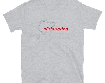 Può includere: Una maglietta grigia a maniche corte con un contorno bianco del circuito di gara del Nürburgring e la parola "Nürburgring" in rosso.
