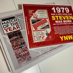 May include: A red and white box with the text "Match of the Year" on the front. The box is open and a red and white poster with the text "1979 Was a Very Good Year Steven Was Born and the Reds Were Flying High" is visible. The poster also includes a smaller red and white poster with the text "Liverpool vs Everton" and a cartoon image of two football players.