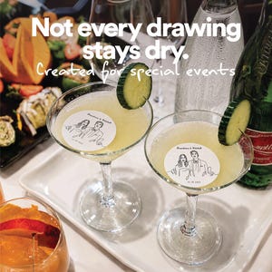 May include: Two martini glasses filled with a pale yellow cocktail, each featuring a round white garnish with a line-art illustration of a couple and the text "Franchesca & Mitchell 11.18.2023". Text overlay reads "Not every drawing stays dry. Created for special events".