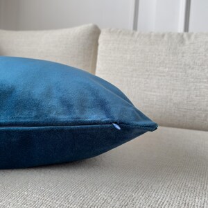 May include: A teal blue velvet pillow with a zipper closure.